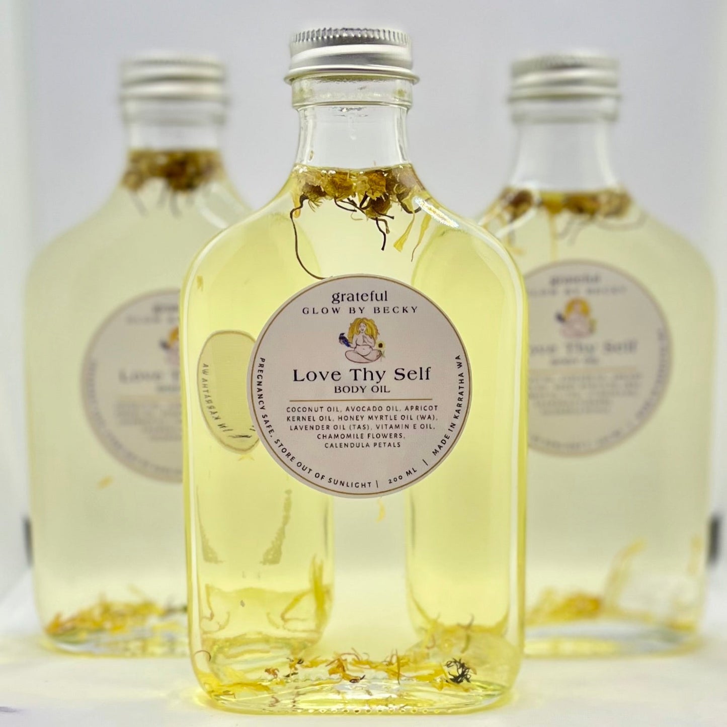 Three bottles of 'Love Thy Self' product with visible labels on a white background