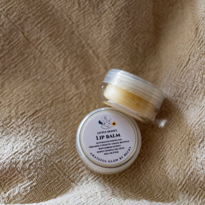 Two small round jars of lip balm placed on a textured beige fabric background.